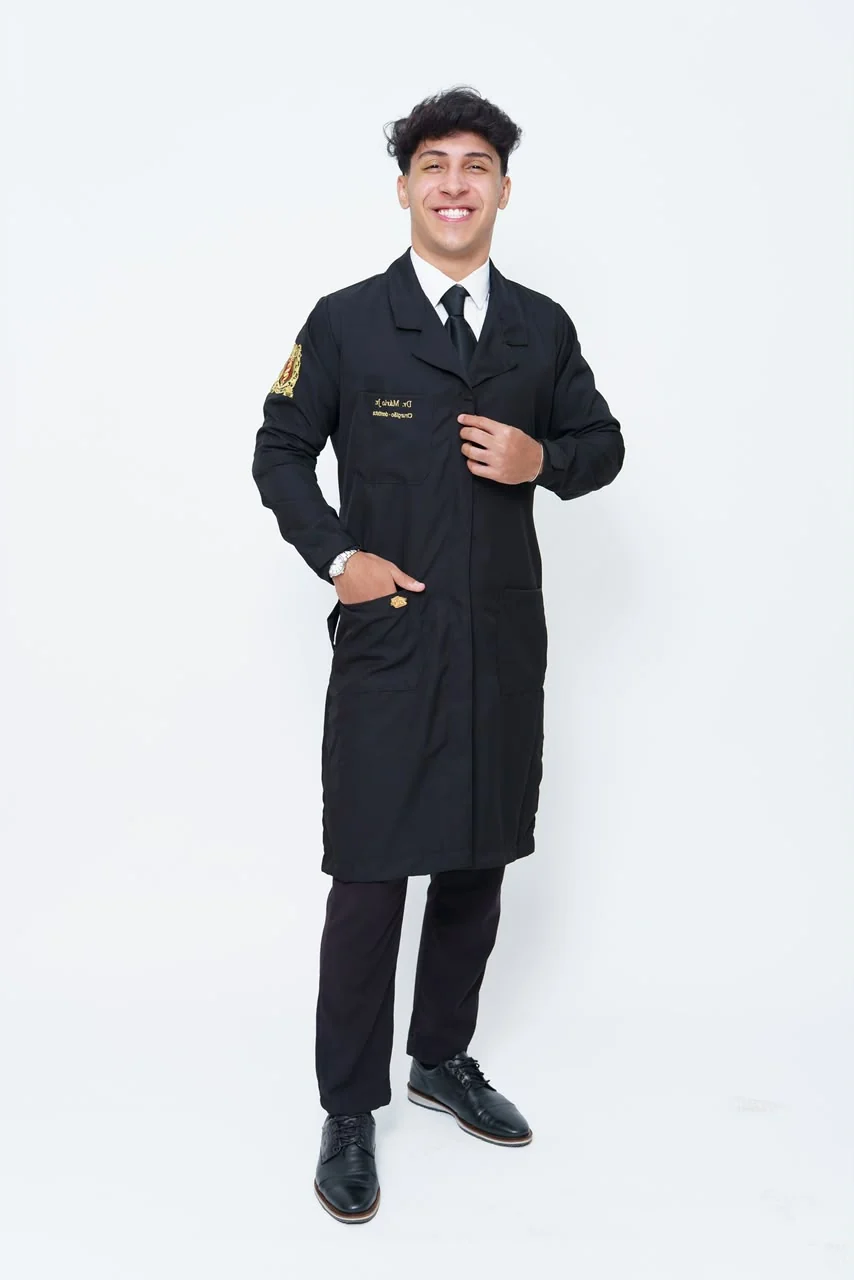 Mário Júnior de corpo inteiro, de jaleco preto, sorrindo